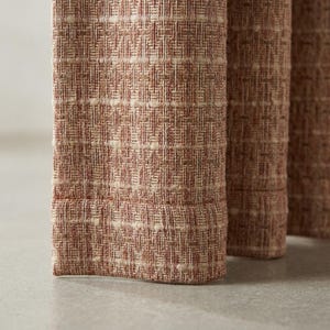 May include: Close-up of three textured fabric panels in shades of red and beige. The fabric has a woven appearance with a subtle pattern. The panels are standing upright, suggesting they are part of a larger piece of furniture or decor.