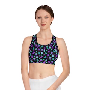 May include: Black sports bra with a colorful pattern of gummy bears, candies, and other sweets in shades of purple and teal. The bra has a scoop neck and a racerback design.