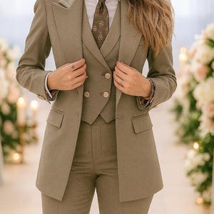 Könnte beinhalten: Ein dreiteiliger olivgrüner Anzug mit passender Krawatte und weißem Hemd mit Kragen. Der Anzug besteht aus einem Blazer, einer Weste und einer Hose. Der Blazer hat zwei Vordertaschen und einen doppelreihigen Verschluss. Die Krawatte hat ein dezentes Muster.
