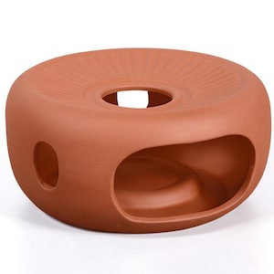 Op de afbeelding: Een terracotta-kleurig, donutvormig keramisch object met een centraal gat en een grote opening aan één kant. Het bovenoppervlak heeft een geribbelde textuur. Er zijn twee kleinere openingen aan de zijkanten. Waarschijnlijk een decoratief of functioneel item.