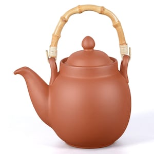 Può includere: Una teiera color terracotta con manico in bambù. La teiera ha un corpo arrotondato, un beccuccio curvo e un coperchio con un piccolo pomello. Il manico in bambù è fissato con dettagli intrecciati. Questa teiera è adatta per preparare il tè.