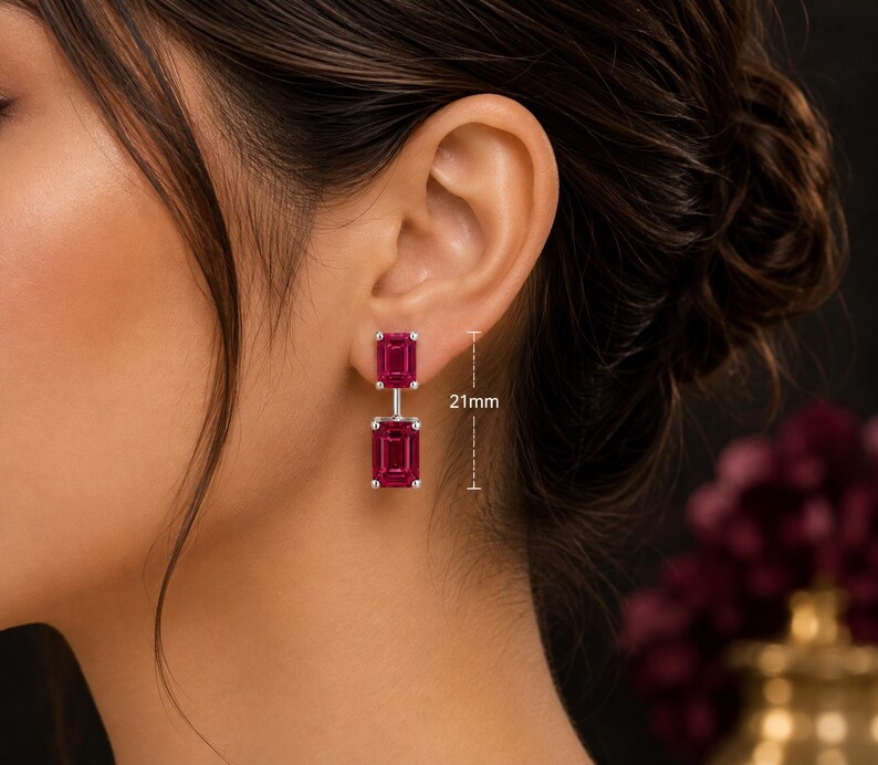 Pode incluir: Um par de brincos pendentes com duas pedras retangulares de corte esmeralda em vermelho rosado profundo, engastadas em metal prateado. Os brincos t&ecirc;m um comprimento vertical total de 21mm, conforme indicado pelas linhas de medi&ccedil;&atilde;o vis&iacute;veis.
