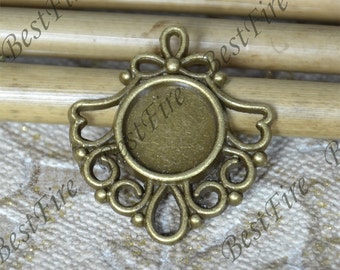 May include: A gold-toned metal pendant with a round, clear glass bezel. The pendant features a decorative, ornate design with a bow at the top.