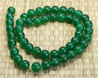 May include: A strand of round, green jade beads. The beads are smooth and polished, and they are strung on a clear thread.