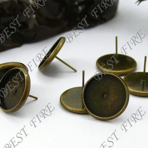 May include: Five antique gold-toned earring settings with round bezels and posts. The bezels are designed to hold a cabochon stone or other embellishment.