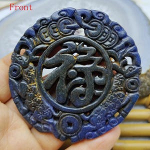 May include: A dark blue carved pendant with a circular design. The pendant features a central character within a circle, surrounded by intricate patterns and dragon-like figures. The word "front" is visible at the top.