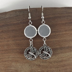 May include: Silver dangle earrings with a round glass cabochon and a dragonfly charm.