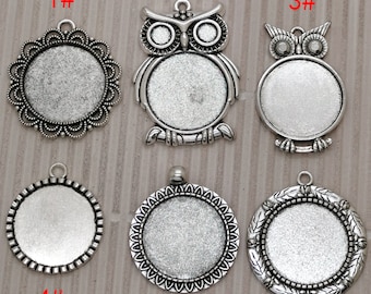 May include: Six silver-toned pendant charms with different designs. The charms are round and have a blank space in the center. The designs include a floral pattern, an owl, and a simple circle.