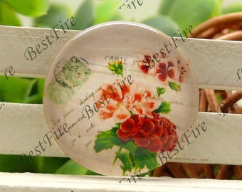 Puede incluir: Cabujón de vidrio redondo con un diseño floral de flores rojas y rosas, hojas verdes y escritura vintage. El cabujón tiene una forma ligeramente abovedada y probablemente se utiliza para joyería o manualidades.