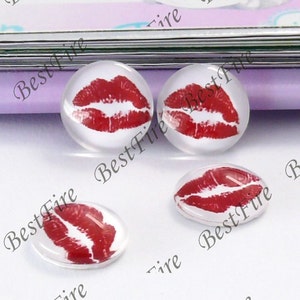 May include: Four clear glass cabochons with red lips printed on them. The cabochons are round and have a glossy finish.