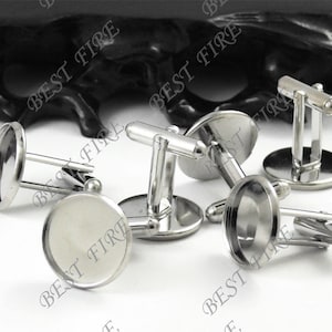 Puede incluir: Cinco gemelos de plata con insertos circulares redondos, lisos, plateados, en blanco y circulares. Los gemelos son de metal y tienen un acabado pulido.