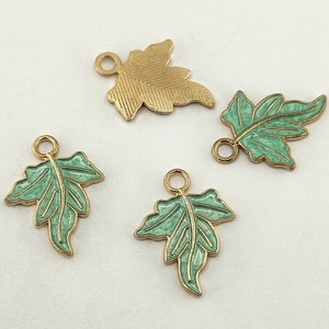 May include: Four gold-tone leaf charms with green enamel. Two of the charms are simple leaf shapes, and two are more detailed with veins and a textured surface.