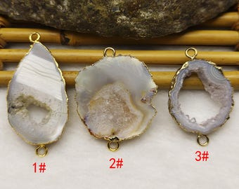 Könnte beinhalten: Drei natürliche Achat-Anhänger mit goldfarbenen Metallrändern und Schlaufen. Die Anhänger haben verschiedene Formen: tropfenförmig, unregelmäßig und oval. Jeder hat ein einzigartiges Muster aus grauen und weißen Bändern mit einem kristallgefüllten Zentrum. Beschriftet mit 1#, 2# und 3#.