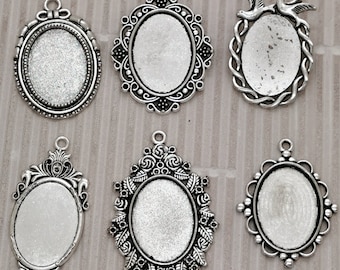 May include: Six silver-toned metal pendant frames with oval-shaped glass inserts. The frames have different decorative designs, including floral, bird, and geometric patterns. The frames are numbered 1 through 6.