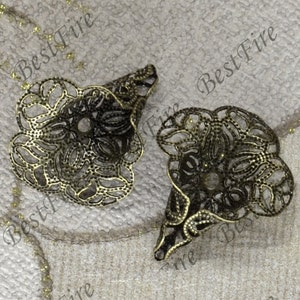 May include: Two antique bronze filigree cone-shaped components. Each piece has an intricate floral design with openwork details. These components are likely for jewellery making or decorative purposes.