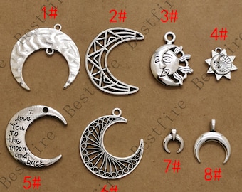 Puede incluir: Una colección de colgantes de metal plateado con diseños celestiales. Los colgantes incluyen lunas crecientes con varias texturas y patrones, un sol con una cara y una estrella con una cara de luna. Ideales para la creación de joyas.