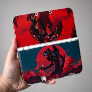 May include: A handheld gaming console featuring a clear protective case over a custom skin. The skin displays a dark, mechanical humanoid figure against a vibrant red circular background, with clouds and birds in a deep blue and red color palette.