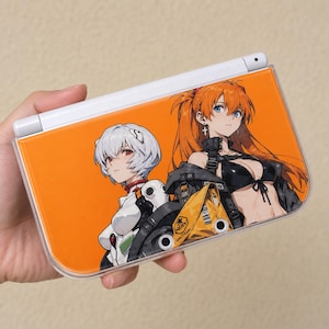 Funda rígida personalizada estilo Evangelion de Rei y Asuka para Nintendo New 3DS XL, con dos pilotos sobre un llamativo fondo naranja.