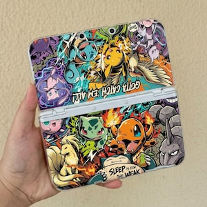 May include: A handheld gaming console featuring a vibrant, multi-colored graphic collage of various Pokémon characters. The top section displays the text "Gotta Catch 'Em All!" and the bottom section includes the text "Sleep is for the weak."