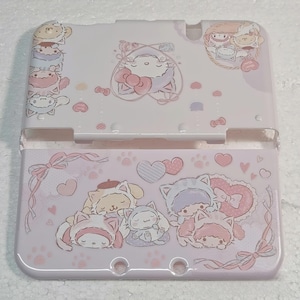 Può includere: Una custodia rosa chiaro per Nintendo 3DS con personaggi dei cartoni animati e disegni a forma di cuore. La custodia ha un design a cerniera ed è decorata con vari personaggi, fiocchi e impronte di zampe. Le sezioni superiore e inferiore sono collegate da una cerniera.