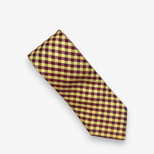 May include: A necktie featuring a repeating gingham check pattern in shades of deep burgundy and bright yellow. The fabric has a woven texture and the tie is cut in a standard pointed shape, displaying a consistent grid design throughout the surface.