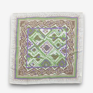 May include: A square, white scarf with a geometric pattern in shades of green, purple, and brown. The scarf has a decorative border with a repeating swirl design. The overall design is symmetrical and eye-catching.