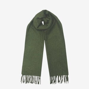 May include: Olive green scarf with fringe detail. The scarf is made of a soft material and is draped over a white background. The scarf is a solid color and has a simple design.
