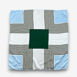 Peut inclure: Un foulard carré présentant un carré central vert foncé uni entouré de panneaux alternés de rayures vert foncé et de motifs à carreaux bleu clair et blanc. Le design est symétrique et le mot Echo est imprimé dans le coin inférieur.