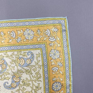 Puede incluir: Un pa&ntilde;uelo de bolsillo cuadrado de tela con un centro de color crema y un patr&oacute;n de cachemira en azul claro y verde oliva. El borde consta de una banda azul claro con motivos de flores blancas y un marco amarillo con enredaderas azules.