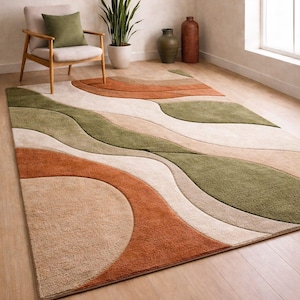 May include: A large rug with an abstract design in shades of orange, green, beige, and cream. The rug has a soft, textured pile and adds a modern touch to any living space. The rug is placed on a wooden floor. The rug's dimensions are in cm.