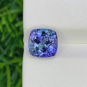 Pu&ograve; includere: Una gemma taglio cuscino con una vibrante gamma di blu e viola. Le sfaccettature della gemma riflettono la luce, creando un effetto scintillante. La pietra &egrave; posta su uno sfondo bianco, evidenziando il suo colore e la sua chiarezza. Un bellissimo esempio di alta gioielleria.
