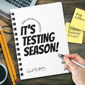 May include: A white spiral-bound notebook with the text "IT'S TESTING SEASON!" in bold black letters. The phrase "SEND CAFFEINE & CHOCOLATE!" is above the main text. Two yellow sticky notes read "Buy notebook" and "Distract training 12-5 p.m."