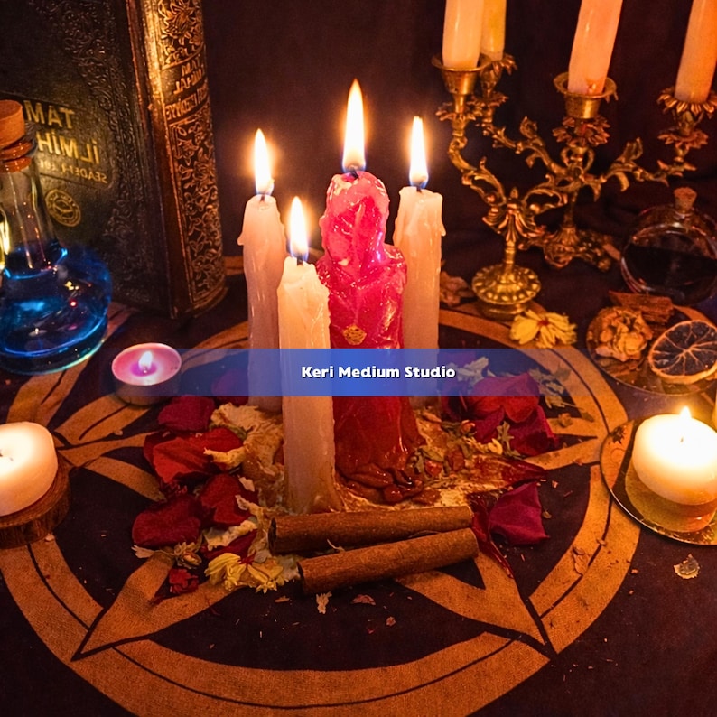 May include: A mystical scene featuring lit candles of various sizes and colors, including a central red candle. The arrangement includes a pentagram, dried flowers, cinnamon sticks, and a vintage book. The text "Keri Medium Studio" is visible.