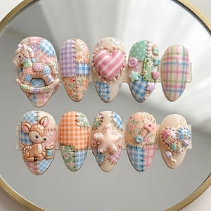 May include: A set of ten almond-shaped press-on nails featuring a patchwork design with pastel colours, floral patterns, and gingham checks. Embellishments include a 3D rocking horse, a heart, a deer, a star, a safety pin, and a rattle.