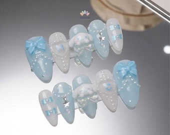 May include: A set of ten press-on nails in various designs. The nails feature a light blue and white color scheme with glitter, bows, and small character embellishments. Some nails have a bow accent, while others have a heart or star design.