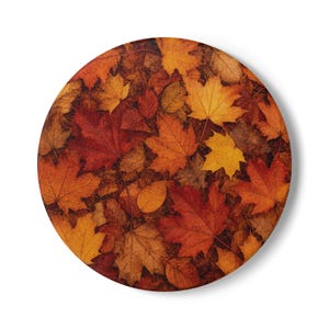 May include: A circular decorative plate featuring a high-resolution photographic print of fallen autumn leaves. The surface displays a dense, overlapping pattern of maple and other foliage in vibrant shades of red, orange, yellow, and brown.