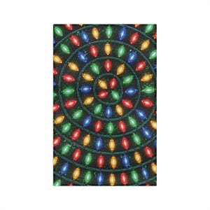May include: A rectangular fabric print featuring a repeating pattern of concentric circles formed by strings of multicolored Christmas lights. The bulbs are red, green, blue, yellow, and orange, arranged against a dark, textured background.