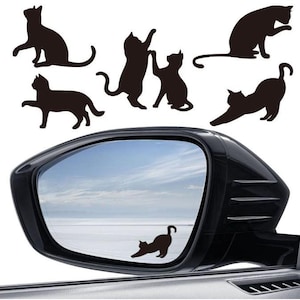 May include: Black cat silhouette decals in various poses, including stretching, sitting, and playing. The decals are displayed on a white background and reflected in a car side mirror. Cat-themed decor.