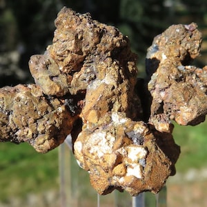 Könnte beinhalten: Ein Cluster aus rauen, strukturierten Gesteinen mit einer Mischung aus Braun-, Gold- und Weißtönen. Die natürliche Mineralformation hat eine unregelmäßige Form und scheint ein Roh-Erz-Exemplar zu sein.