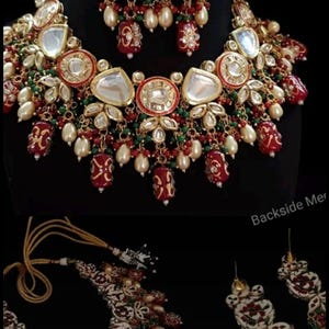 May include: An ornate jewelry set featuring a necklace and matching earrings. The necklace and earrings are gold-toned with red, green, and white accents, and dangling pearl-like beads. The set is displayed against a black background.
