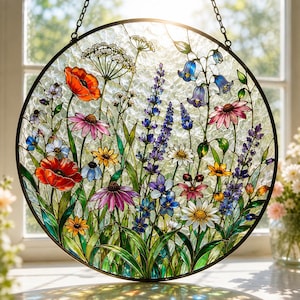 May include: A circular stained glass suncatcher featuring a vibrant meadow of wildflowers including red poppies, purple lavender, blue bellflowers, and white daisies. The textured glass panel is framed in black metal and hangs by a chain.