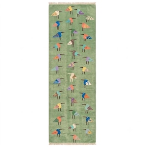 May include: A rectangular area rug in a muted sage green featuring a repeating pattern of small, stylized birds in various colors including blue, orange, yellow, purple, and white. The rug has a short fringe along the top and bottom edges.