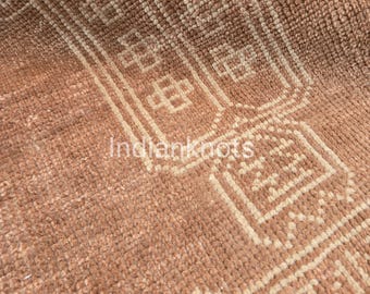 Pode incluir: Um tapete texturizado de cor terracota com um padrão geométrico repetitivo num tom creme mais claro. O design consiste em bordas retangulares e motivos em forma de cruz. A palavra Indianknots está impressa a branco no centro.