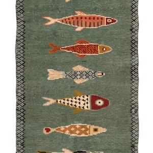 Könnte beinhalten: Ein rechteckiger Läufer in Salbeigrün mit elf stilisierten Fischen in einer vertikalen Reihe. Jeder Fisch zeigt ein einzigartiges geometrisches Muster in Orange-, Rot-, Blau- und Cremetönen. Der Teppich hat einen dunklen Rand und weiße Fransen.