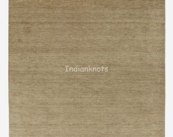 May include: A rectangular, beige rug with a textured surface. The rug has a simple, neutral design, suitable for various interior styles. The text "Indianknots" is visible on the rug.
