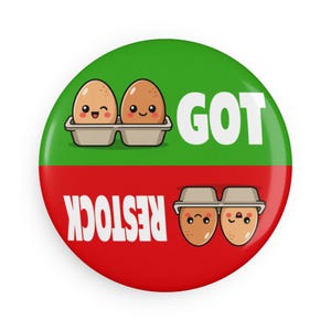 May include: A circular pinback button divided horizontally into a green top half and a red bottom half. The top features two brown cartoon eggs in a carton with the text GOT. The bottom features two inverted brown eggs with the text RESTOCK.