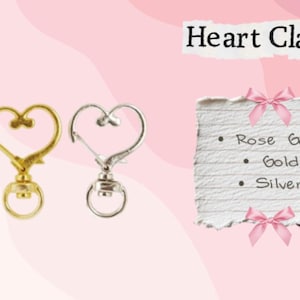 May include: Heart-shaped clasps in rose gold, gold, and silver. The image includes a torn paper note with the words "Heart Clasp" and a list of the clasp colors: Rose Gold, Gold, and Silver.