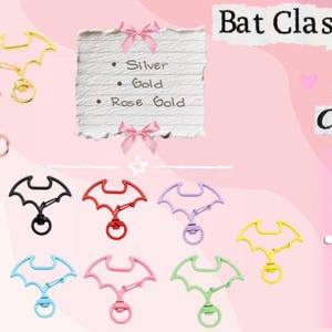 May include: A variety of bat-shaped clasps in multiple colors, including silver, gold, rose gold, black, red, purple, sky blue, pink, green, and yellow. The image includes text that says "Bat Clasp" and lists available colors.