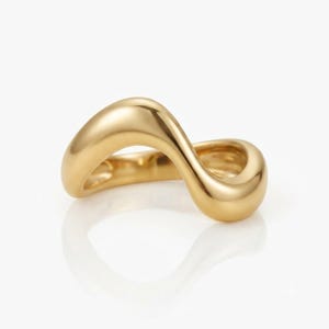 Peut inclure: Une bague dorée présentant un design ondulé lisse et continu. L'anneau possède une surface polie et réfléchissante avec une forme fluide et sinueuse qui crée une silhouette ouverte et asymétrique. Le métal a une finition or jaune chaud.