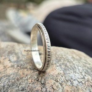May include: A silver-colored ring with a textured band. The ring is set against a neutral background. The text "RudraJewelsArt" is visible on the lower left side of the image. This ring is a piece of jewelry.